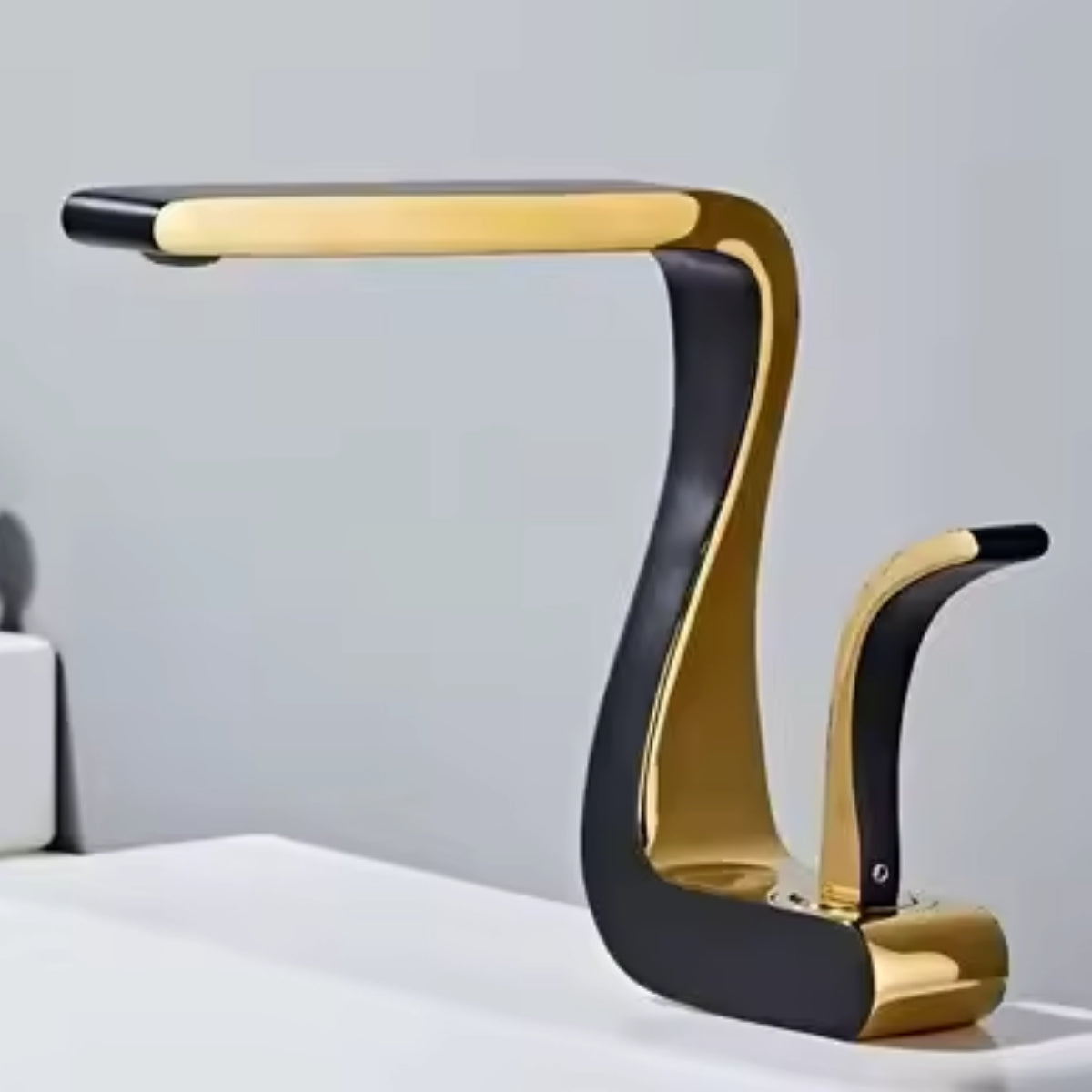 Mitigeur de lavabo MYRAN or et noir au-dessus d'une vasque blanche