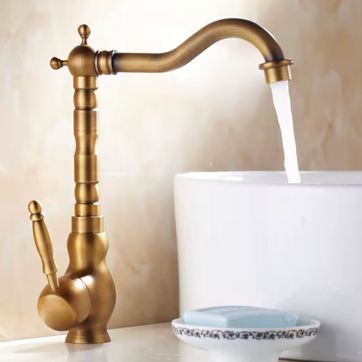 Mitigeur de lavabo ORVAN en laiton vieilli à côté d'une vasque blanche