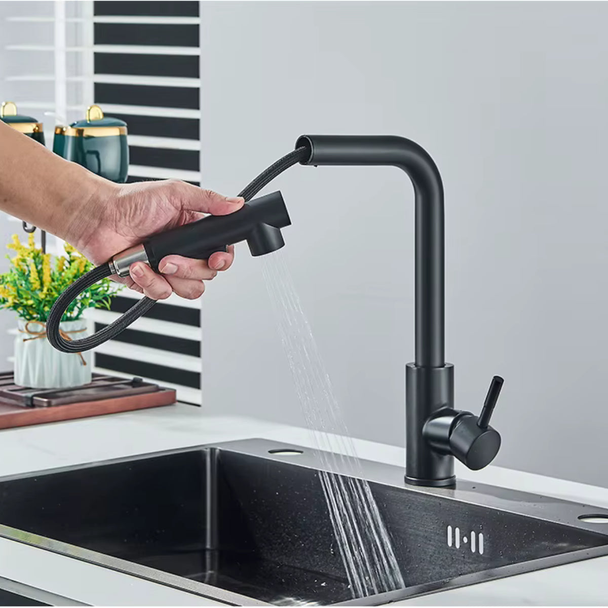 Douchette extractible du robinet de cuisine ASVIK noir tenue à la main