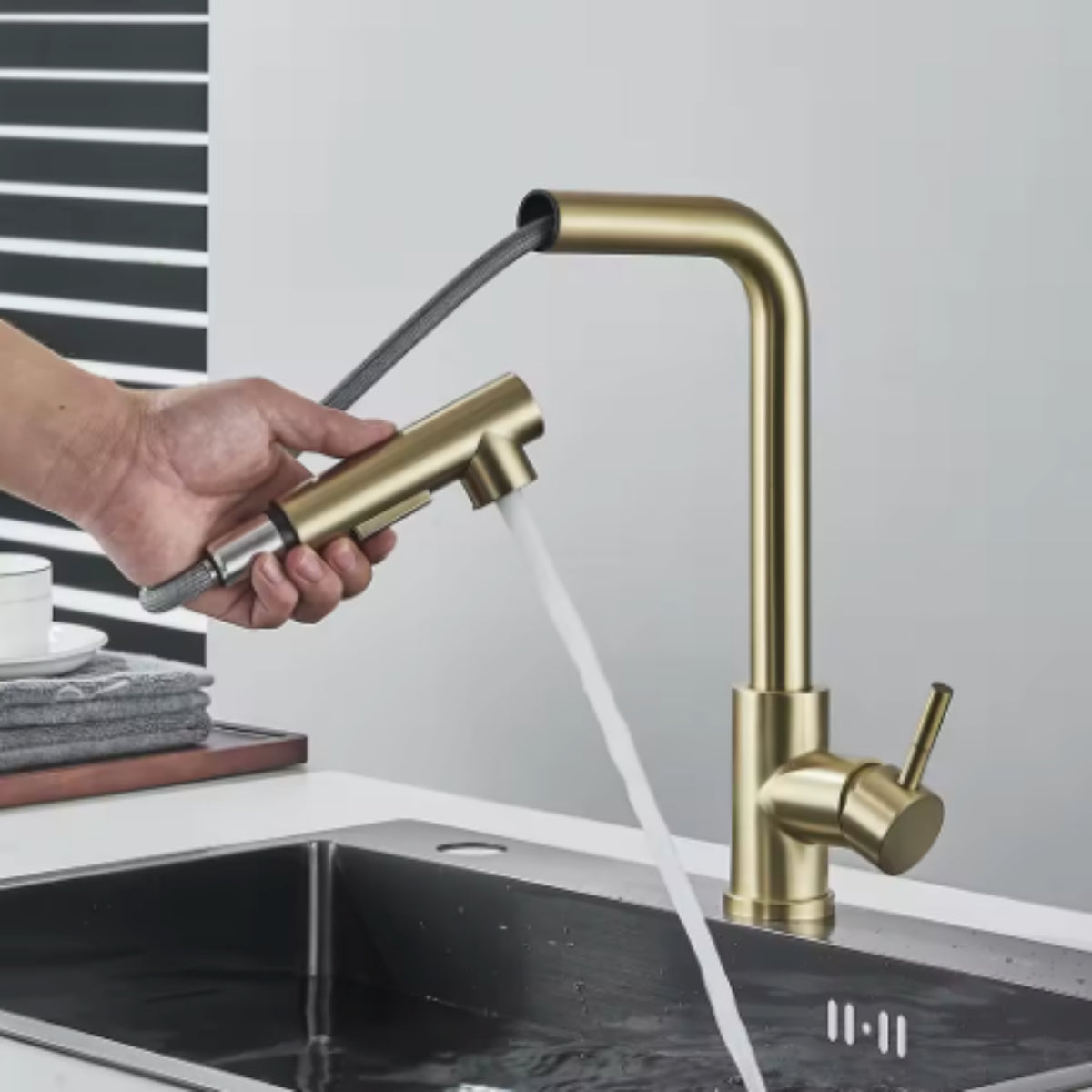 Douchette extractible du robinet de cuisine ASVIK doré tenue à la main