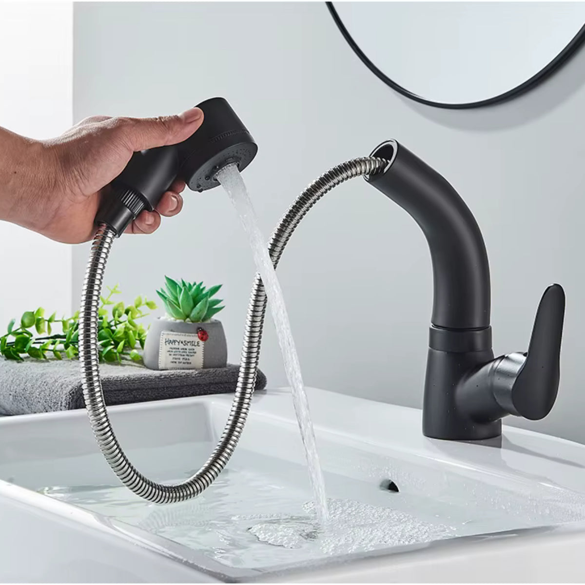 Douchette extractible du robinet LOVIK noir tenue à la main, jet en fonctionnement