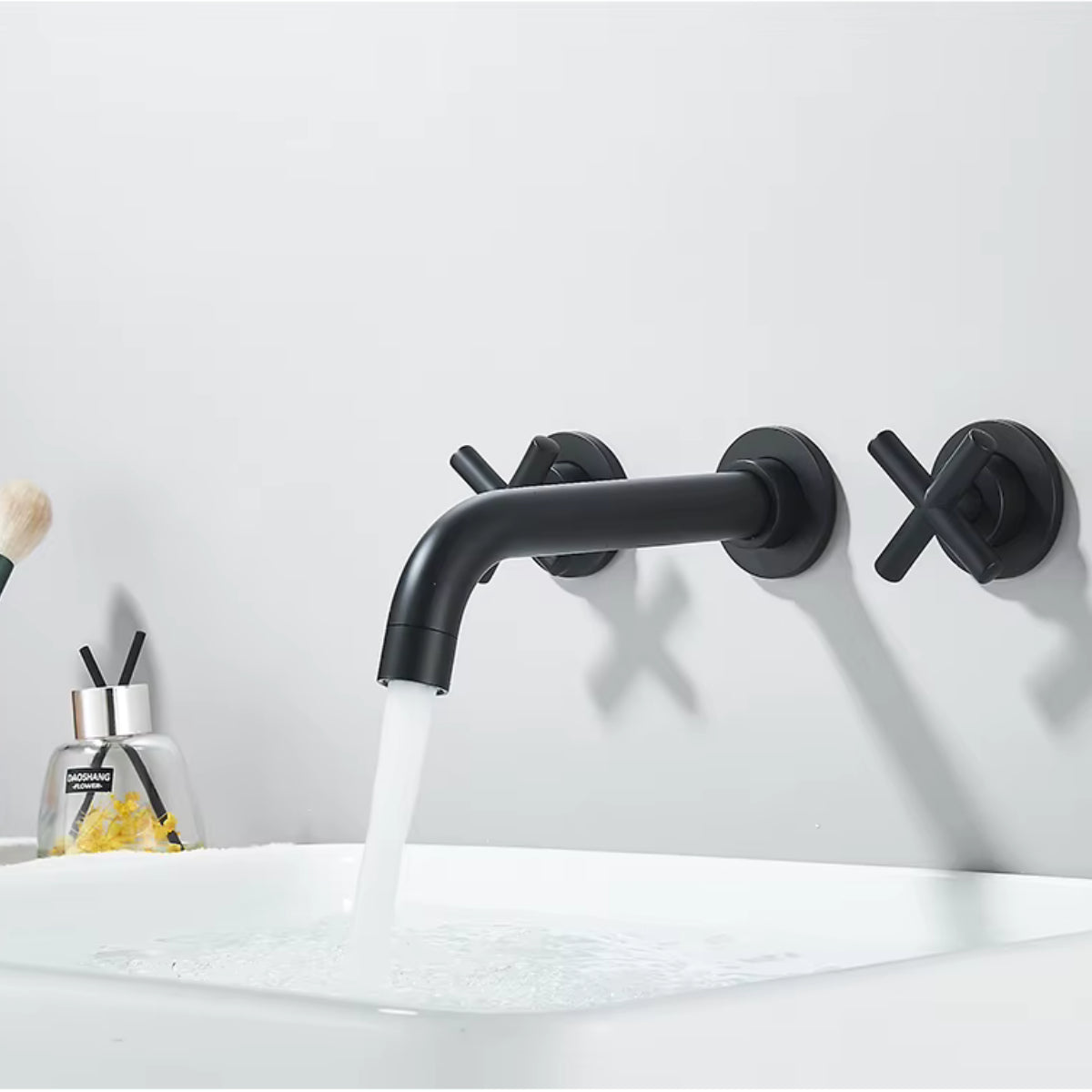 Robinet de lavabo mural HALVAR noir en fonctionnement au-dessus d'une vasque blanche