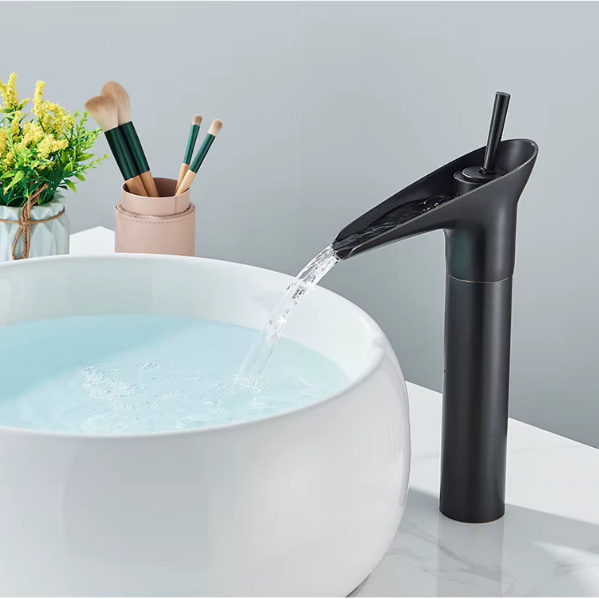Robinet de lavabo INGRA noir en fonctionnement au-dessus d'une vasque ronde