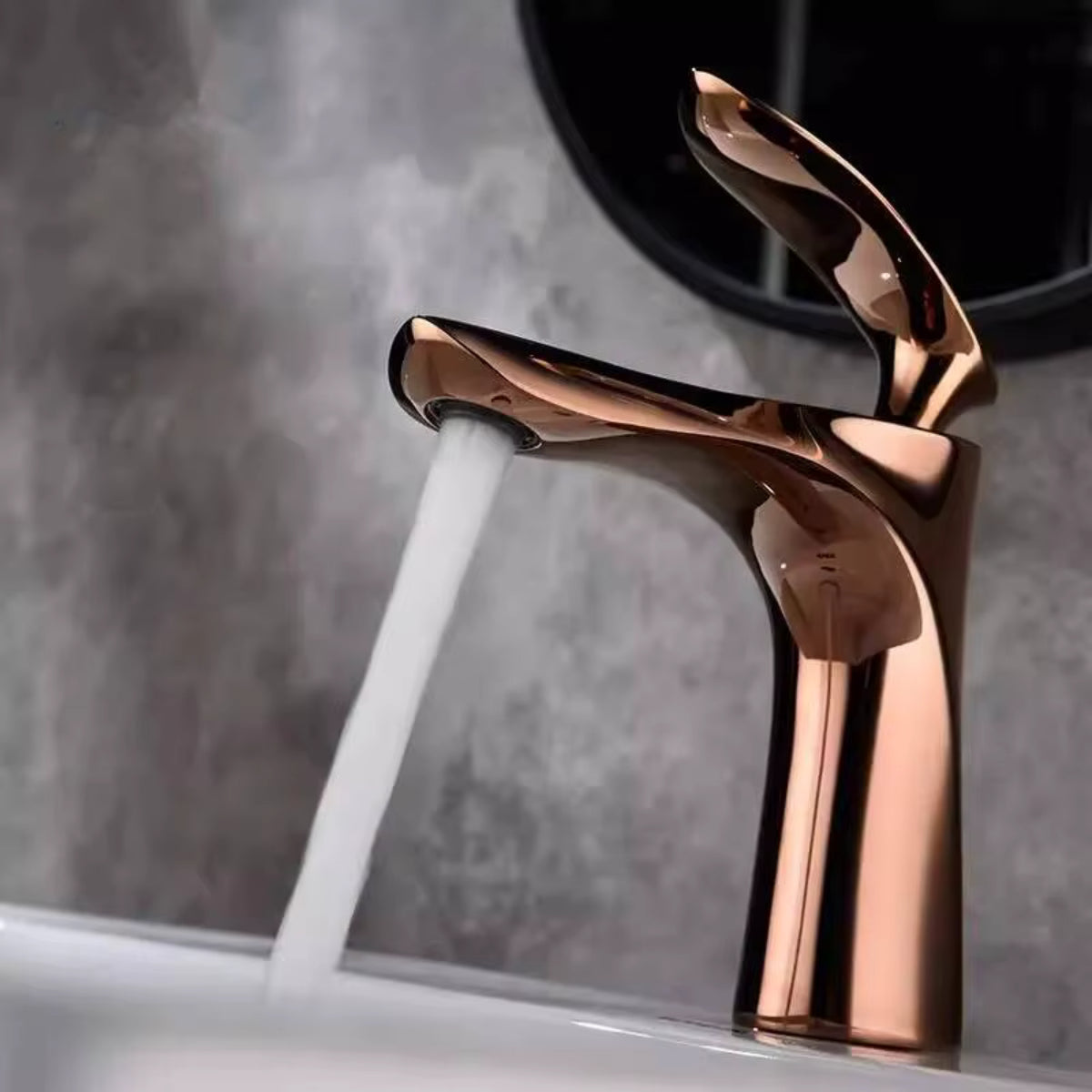 Robinet de lavabo OSVIK or rose en fonctionnement devant un miroir